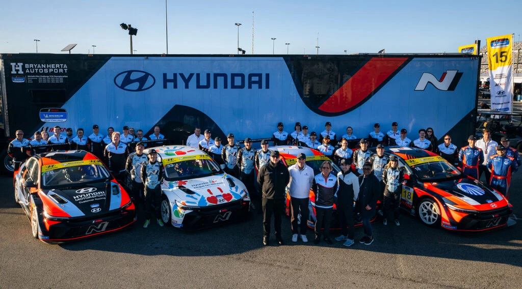 Bryan Herta Autosport crew lined up with four Hyundai N TCR cars in front of the team transporter